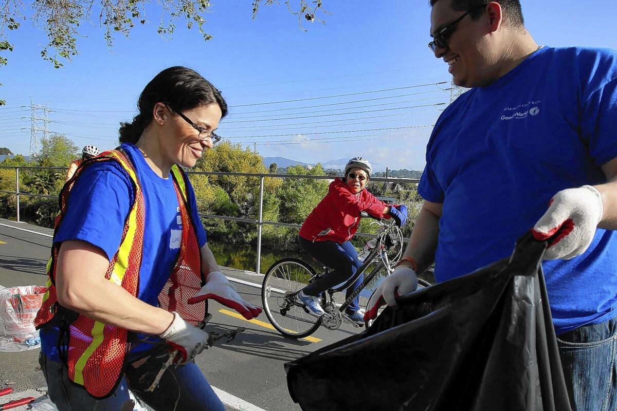 A bicyclist encourages volunteers Lumi Powell and Tomas Marquez, who were removing weeds and dead tree branches alongside the L.A. River as part of an ongoing effort by city officials and the community to restore the waterway.