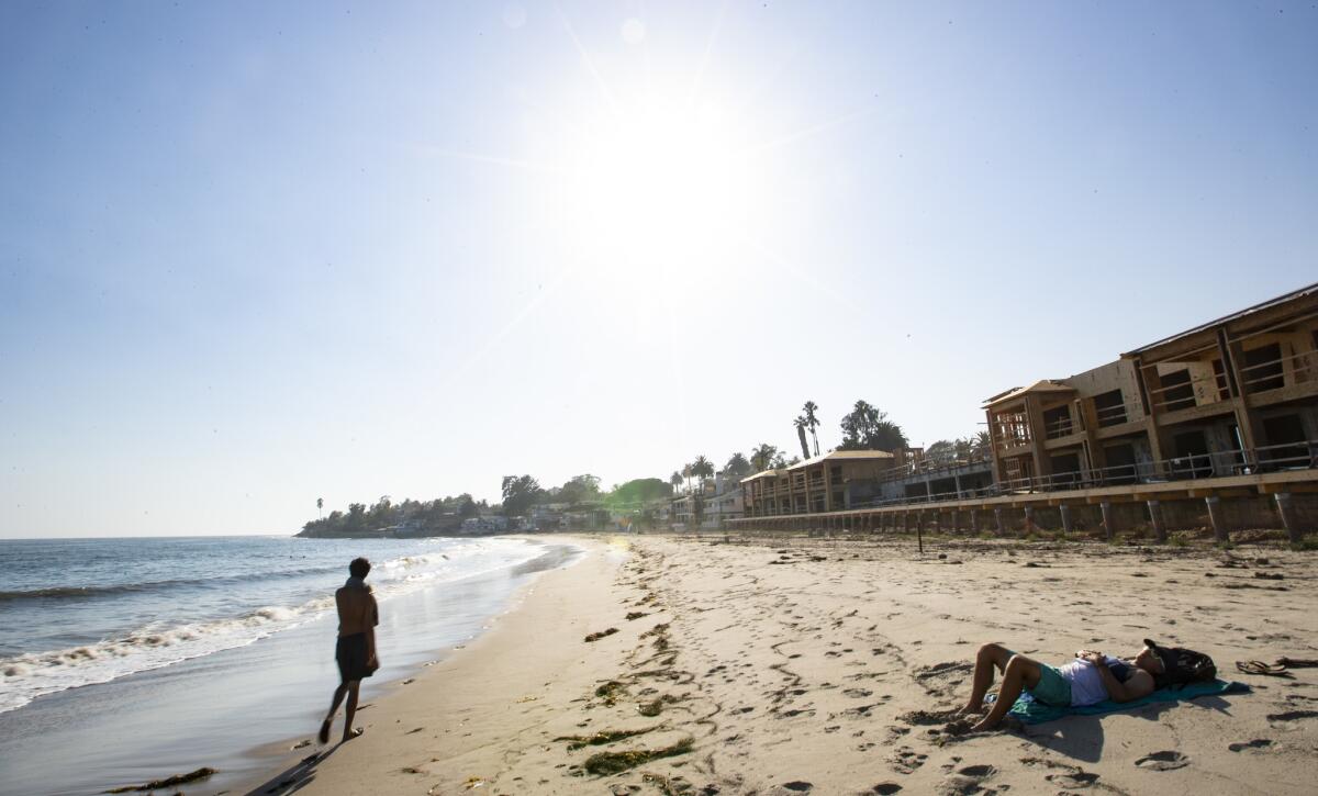 A young woman lounges on the sand in front of the Rosewood Miramar Beach Montecito under construction in Montecito on July 24, 2018.
