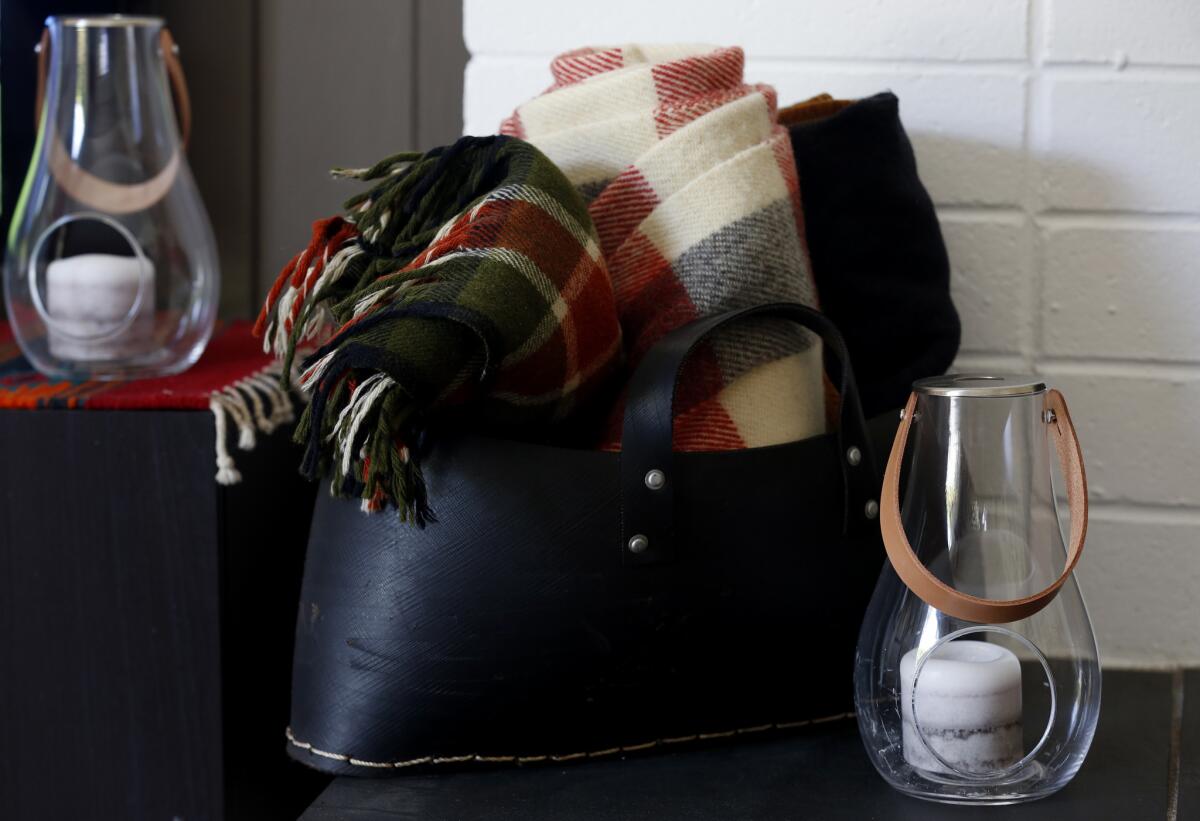 Wool blankets are rolled up into a leather tote near the fireplace.