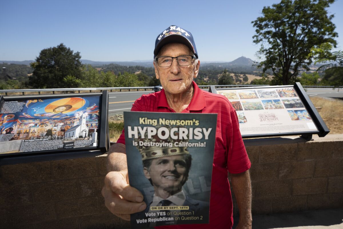 A man with a pamphlet that says King Newsom's hypocrisy is destroying California