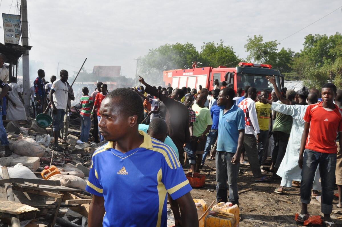 People gather at the scene of a car bombing at the central market in Maiduguri, Nigeria, on July 1.
