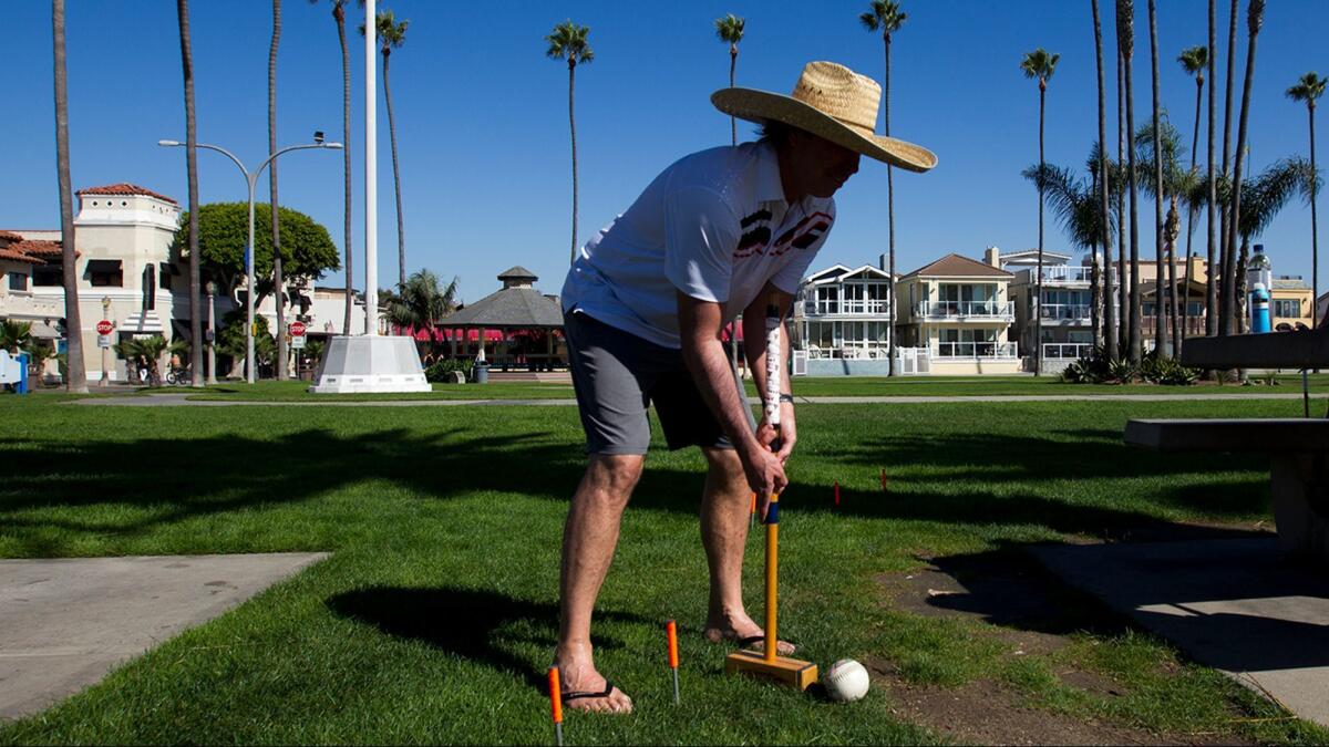Mike Hogan wears a large-brimmed straw hat while playing croquet at Peninsula Park in Newport Beach on Tuesday, where temperatures reached more than 100 degrees.