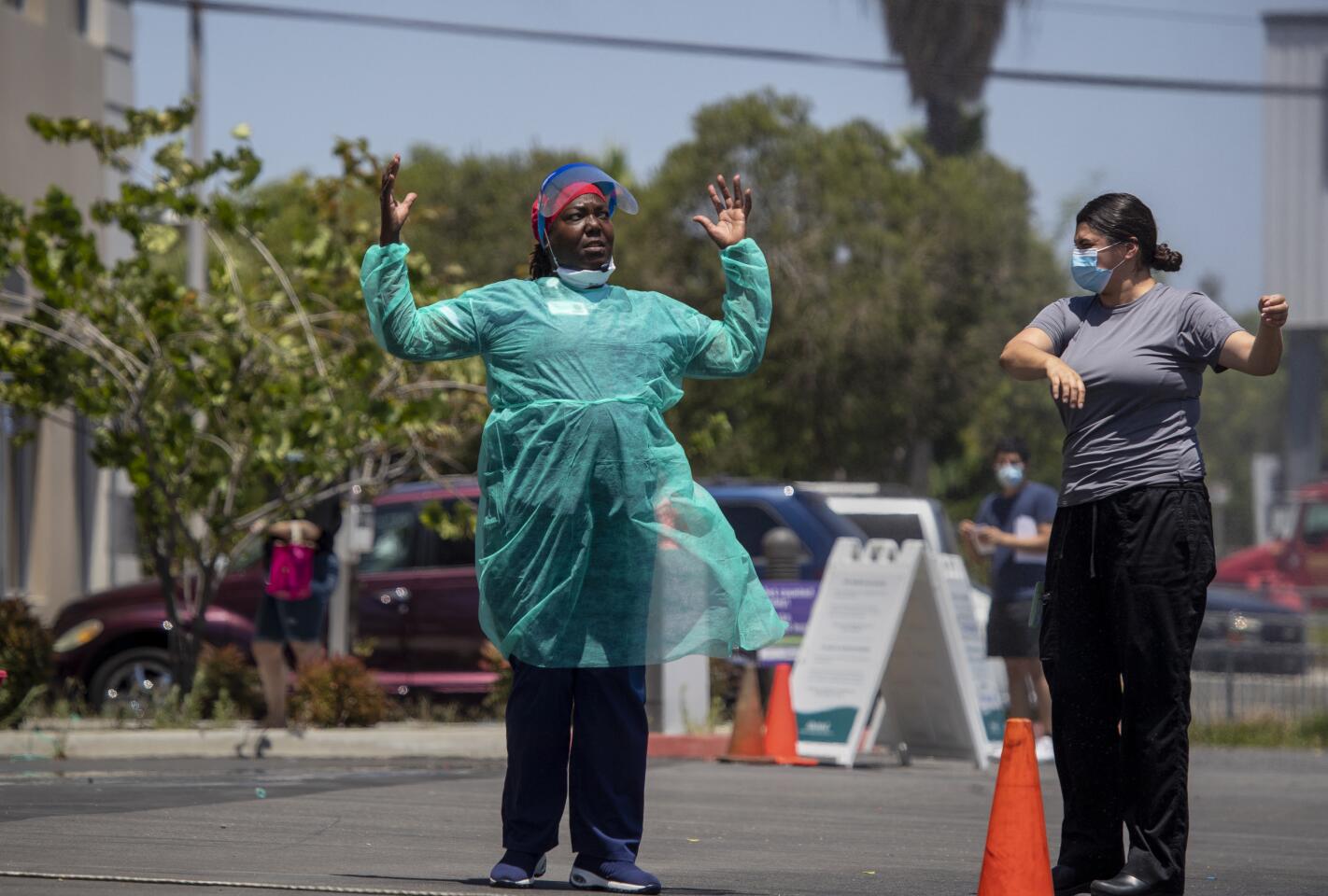 Nurses Wilma Thomas, Viviana Robles stand near a mister to cool off at AltaMed Health Services in Anaheim.