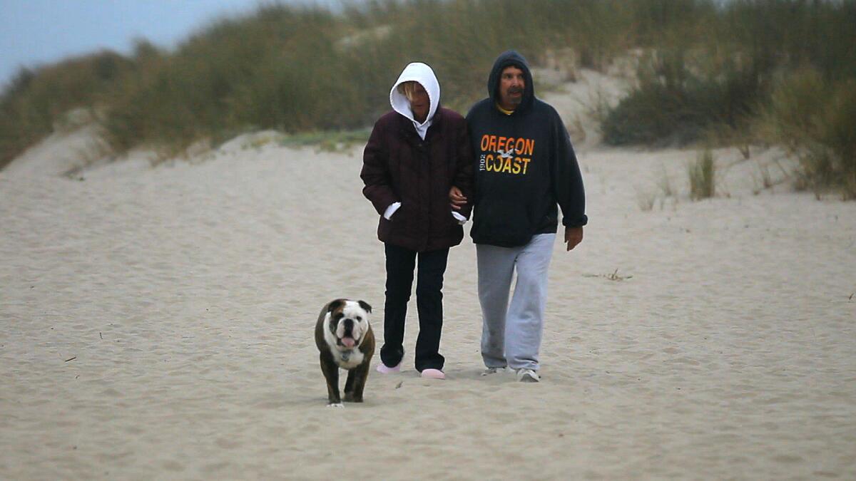 July 2011 photo of Moe and Stu Bryant taking their dog for a walk on the beach outside their Oxnard home.