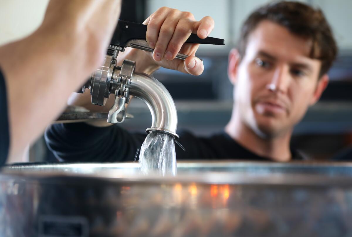 James Busch, production assistant at Pacific Coast Spirits, watches and controls the speed of the transfer of American Brandy into a blending tank before it is then transferred to a barrel where it will be aged, January 29, 2020 in Oceanside, California.
