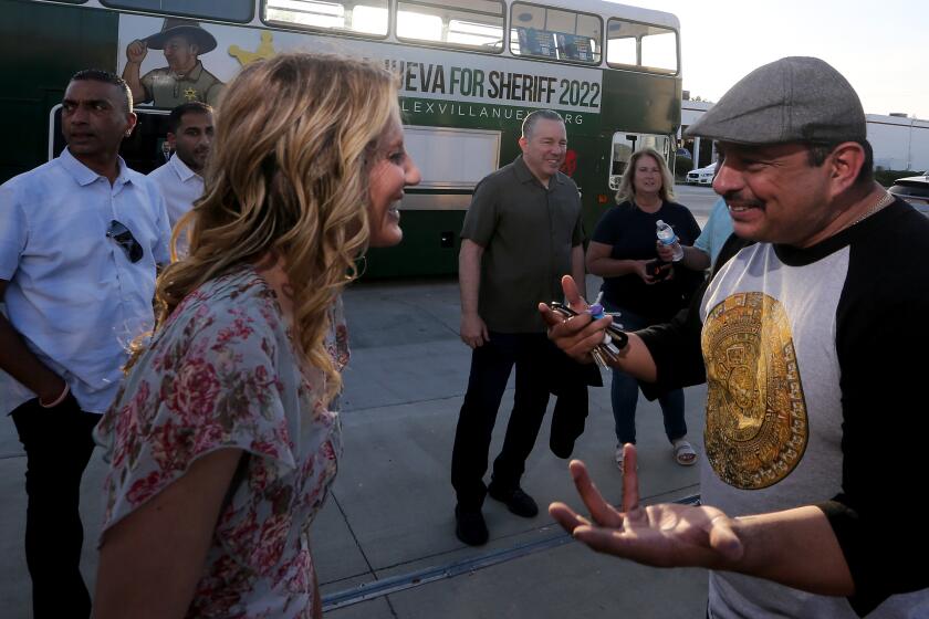 SANTA FE SPRINGS, CALIF. - MAY 26, 2022. Political strategist Javier Gonzalez, right, talks with a supporter of Los Angeles County Sheriff Alex Villanueva, center, during a campaign rally in Santa Fe Springs on Thursday, May 26, 2022. (Luis Sinco / Los Angeles Times)