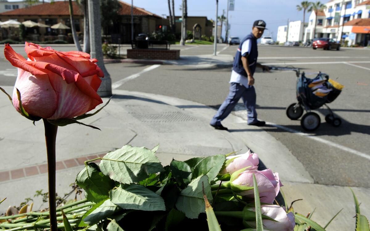 A mail carrier passes by a memorial at the corner of Catalina Avenue and Avanue I in Redondo Beach where a bus struck two pedestrians in early February, killing a man and sending a woman to the hospital with serious injuries.