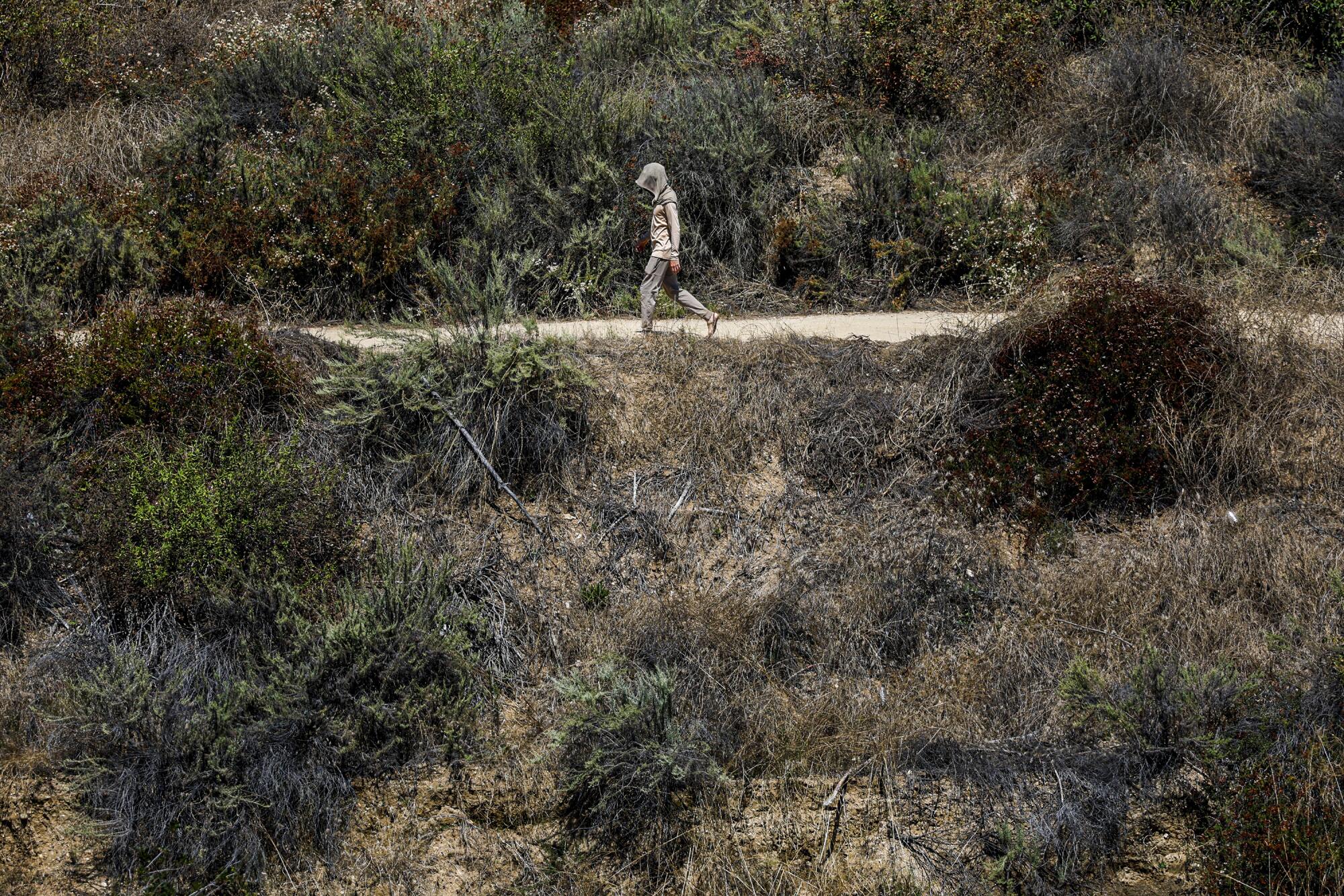 A man hikes a trail at Eaton Canyon in temperatures above 100 degrees. 