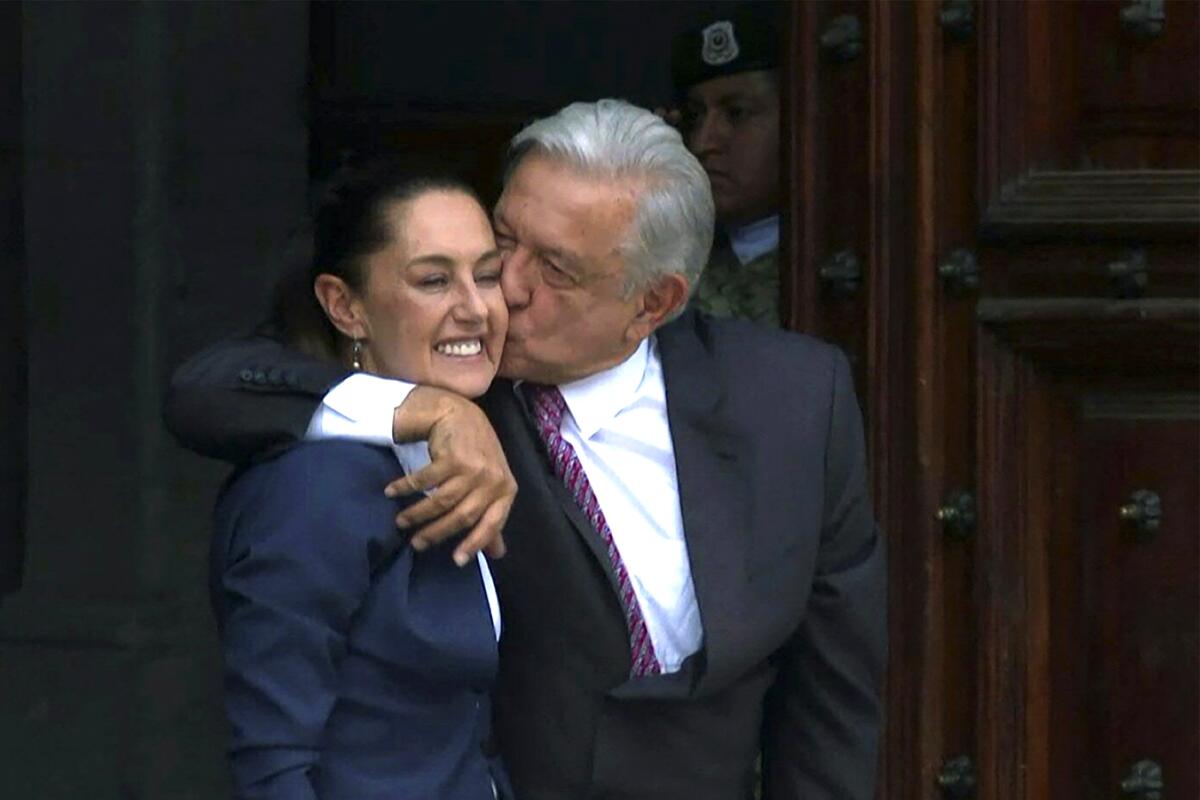 Andrés Manuel López Obrador puts his arm around Claudia Sheinbaum and kisses her cheek.