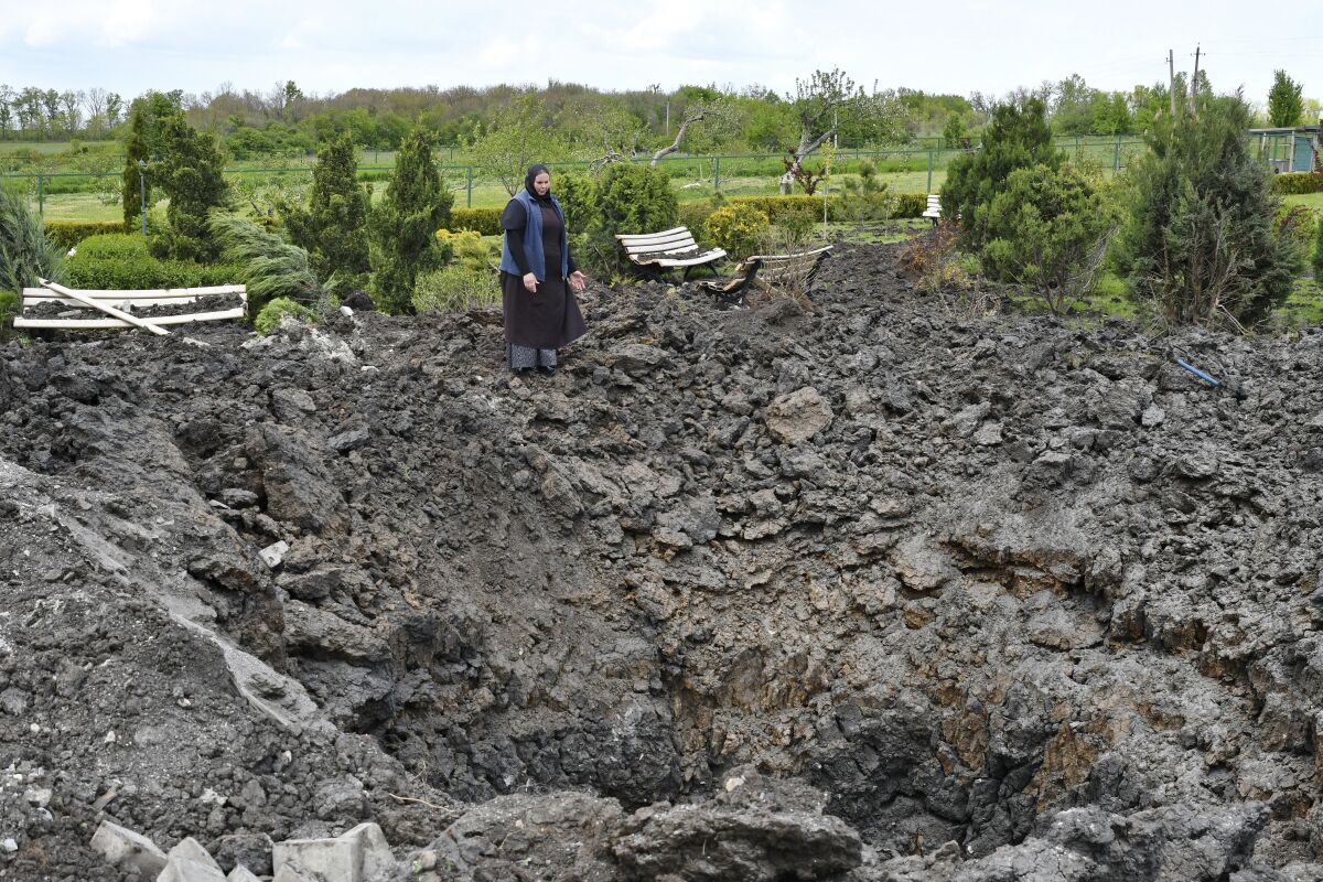 Orthodox Sister Evdokia gestures in front of the crater of an explosion, after Russian shelling next to the Orthodox Skete in honour of St. John of Shanghai in Adamivka, near Slovyansk, Donetsk region, Ukraine, Tuesday, May 10, 2022. (AP Photo/Andriy Andriyenko)