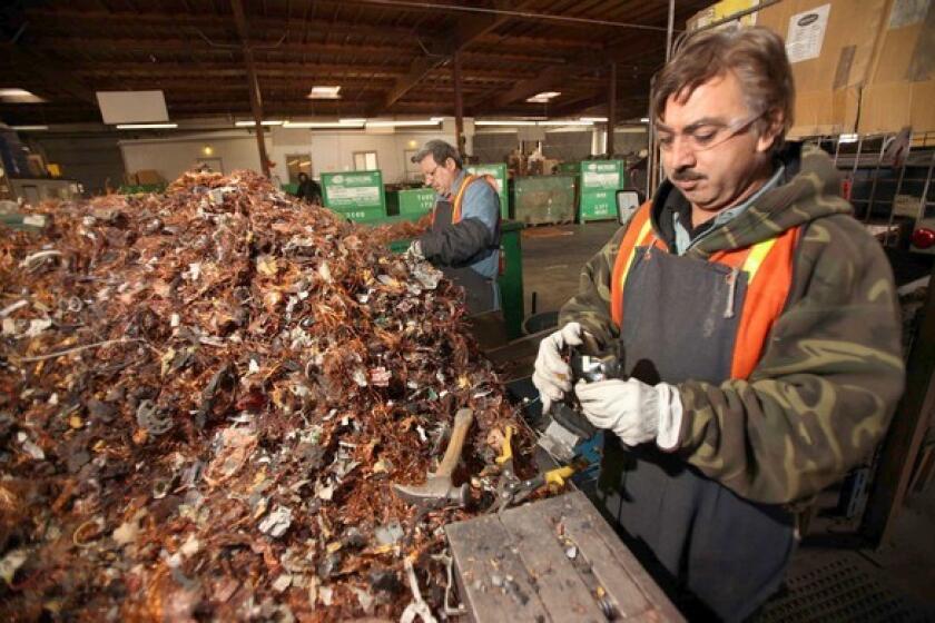 Miguel Ceballos, right, and Lazaro Trejo strip copper from various electronic devices that have been disassembled at the e-Recycling of California processing facility in Paramount.