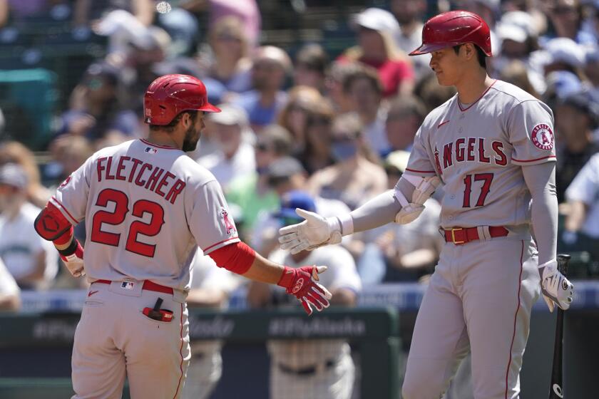 Los Angeles Angels' David Fletcher (22) is greeted at the plate by Shohei Ohtani (17) after Fletcher hit a solo home run during the third inning of a baseball game against the Seattle Mariners, Sunday, July 11, 2021, in Seattle. (AP Photo/Ted S. Warren)