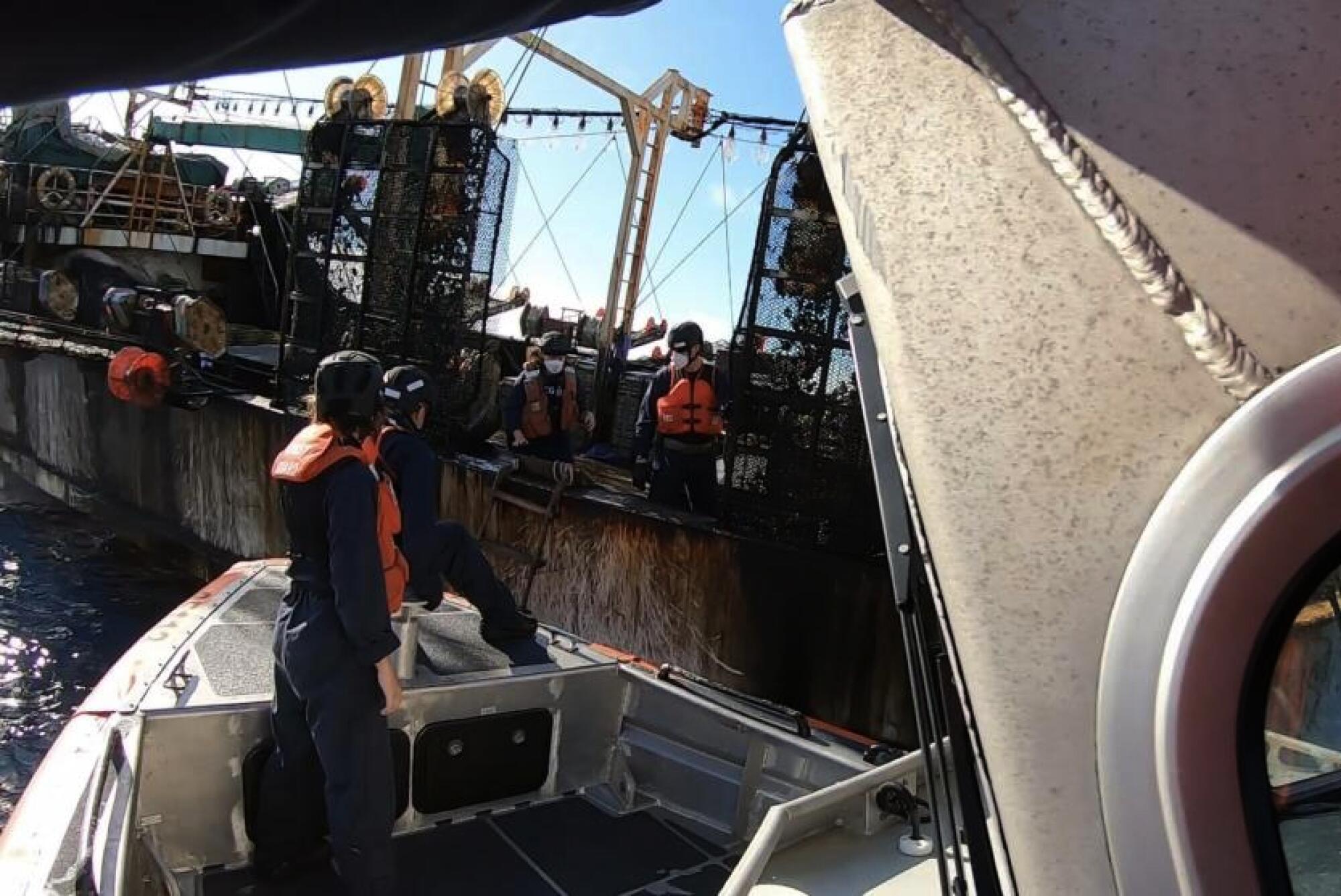 People in a boat approach a fishing vessel 