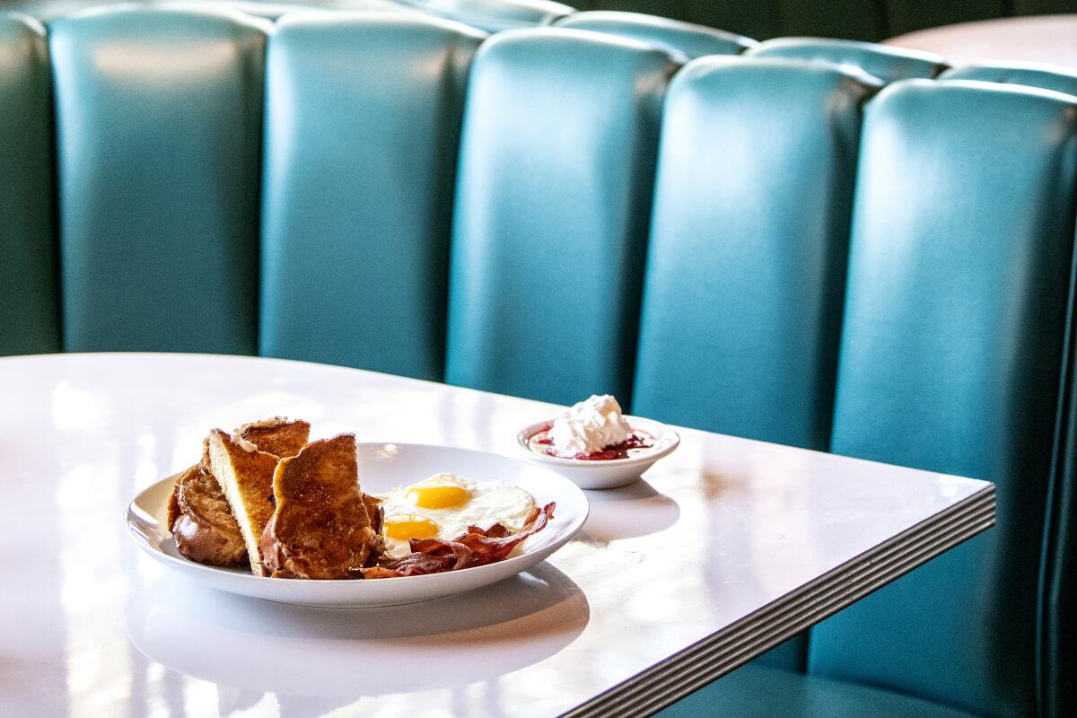 A plate of breakfast on a table at a teal booth.