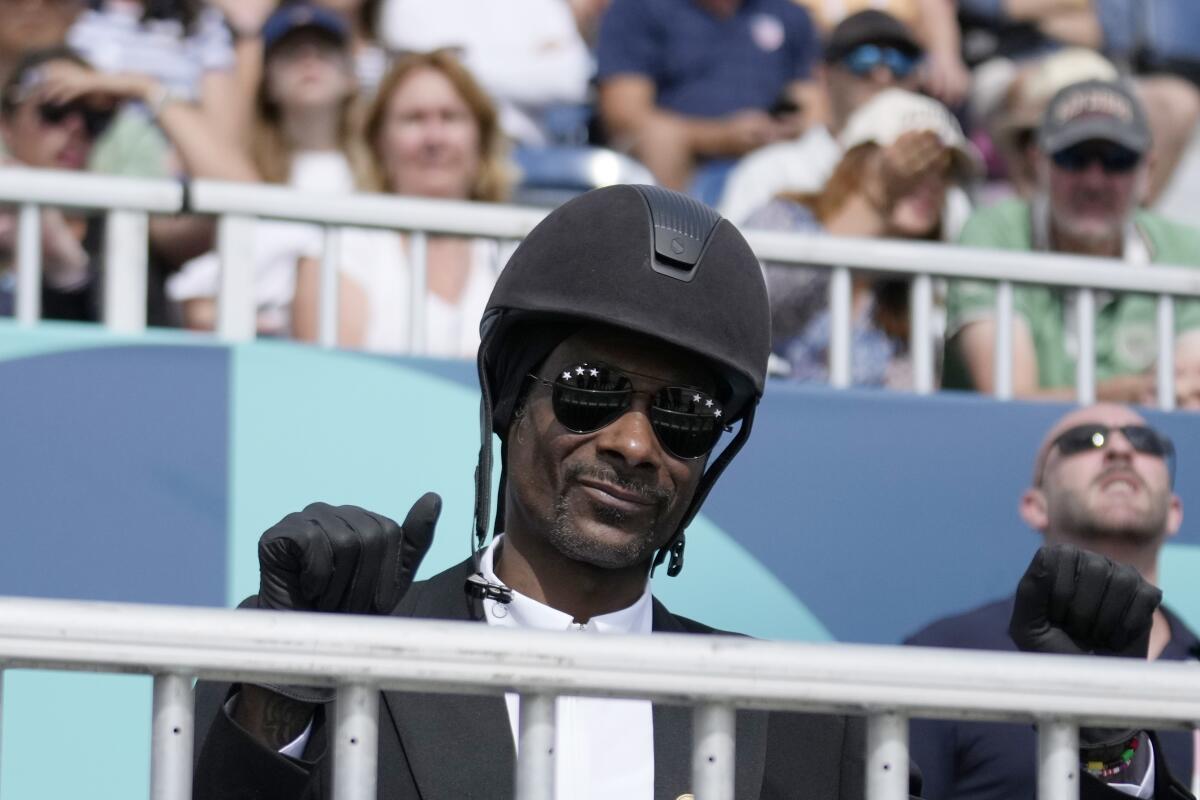 Snoop Dogg levanta el pulgar mientras observa la final del Gran Premio