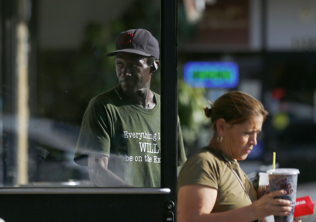 Majesty, a homeless man, holds the door for a customer of a 7-Eleven store along Riverside Drive in North Hollywood.