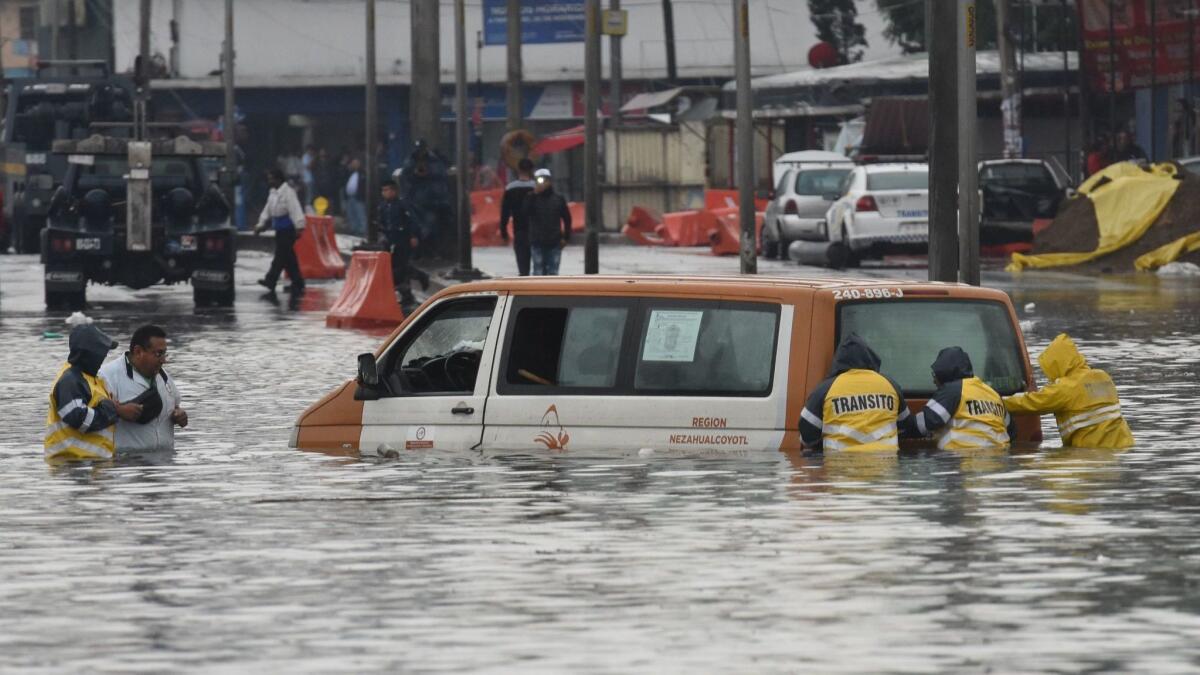 Transit and Civil Protection workers in Mexico attempt to move a van from a flooded street June 14, 2018, as a result of storm Bud in Mexico.