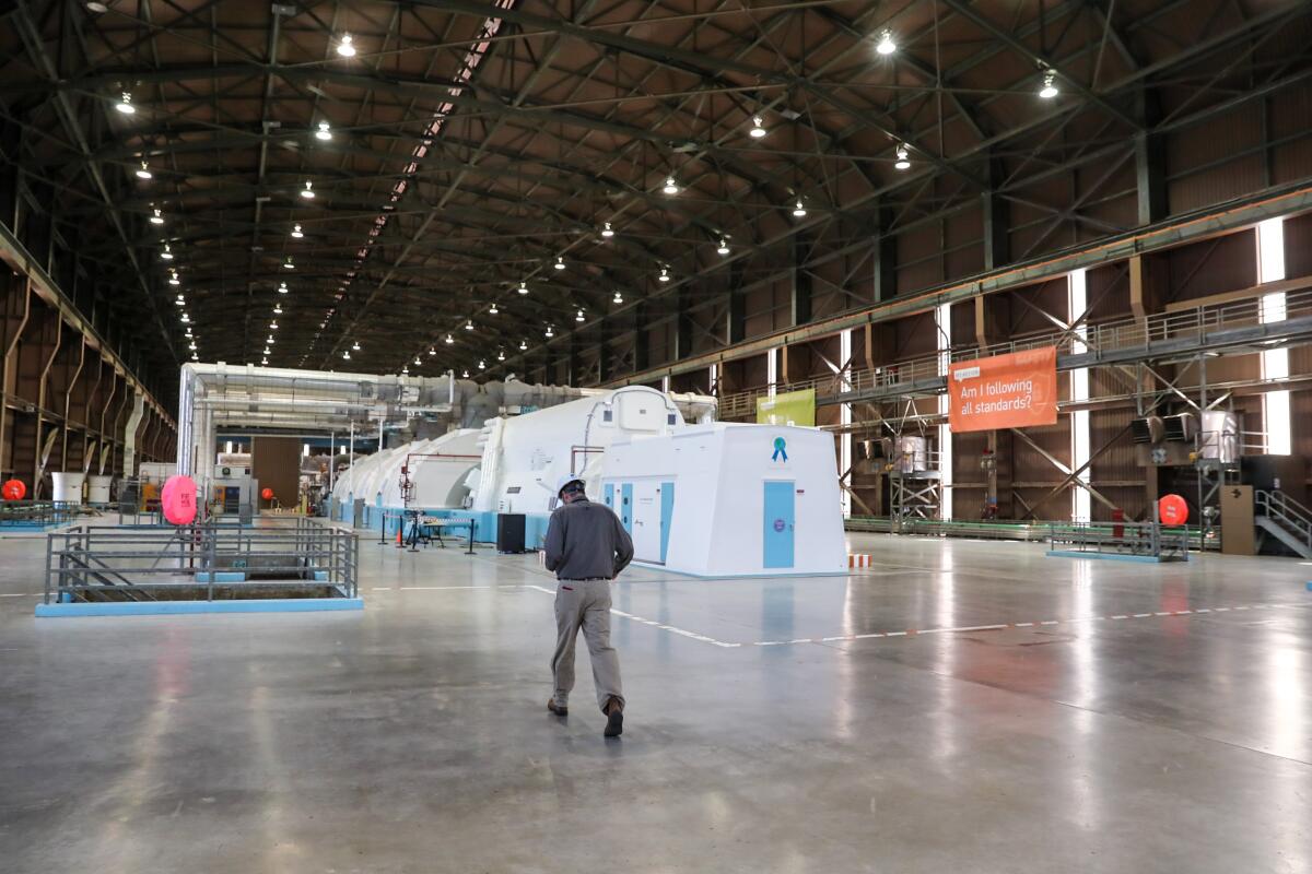 A man walks through a large, warehouselike building.