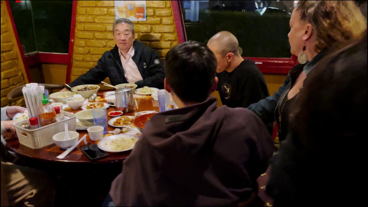 Robert Shinn sitting with others at a round table in a restaurant, facing others in the foreground