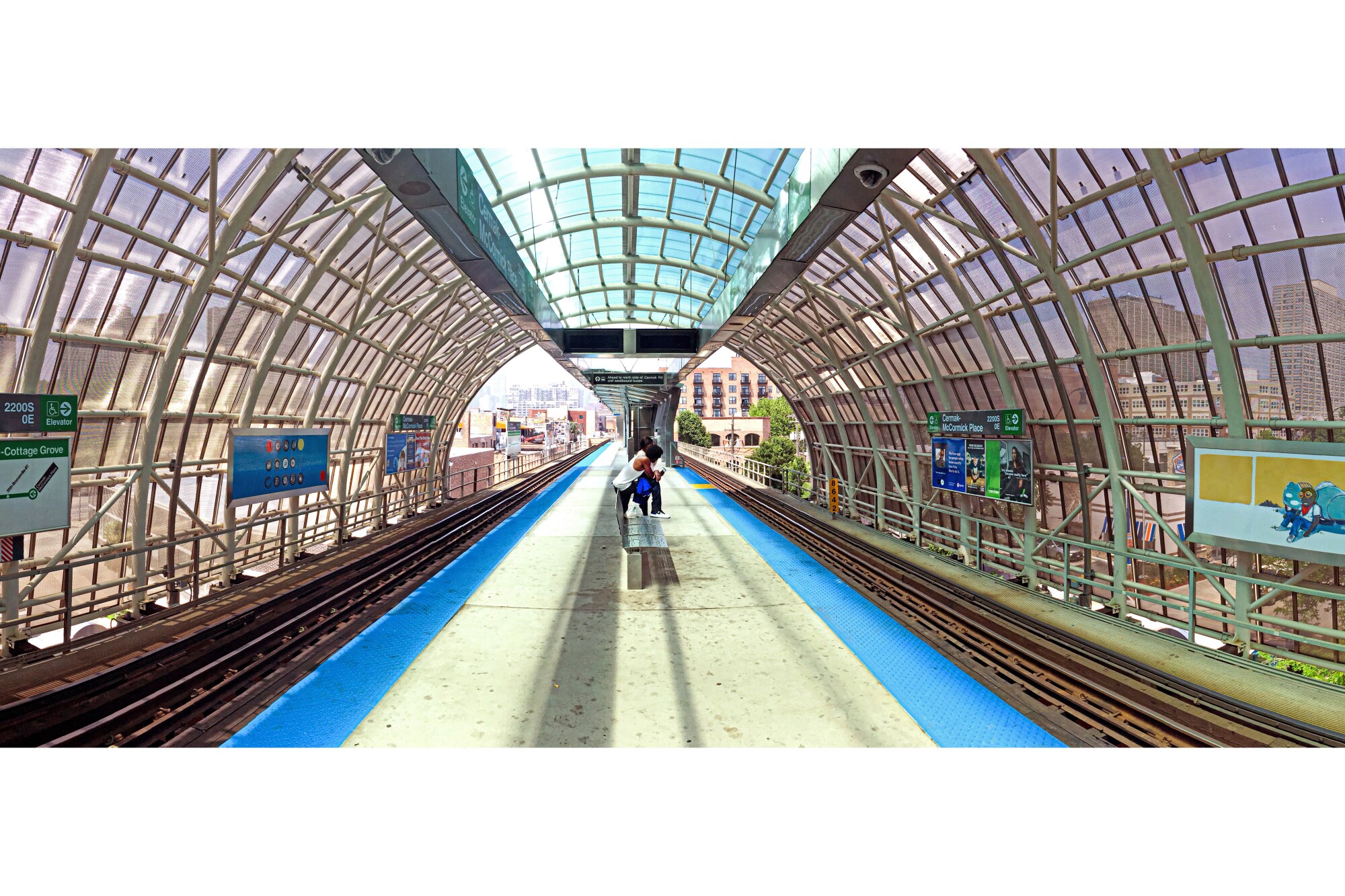 The platform and rails of one stop covered by a glass windowed tunnel on the elevated train system in Chicago. June 2018.