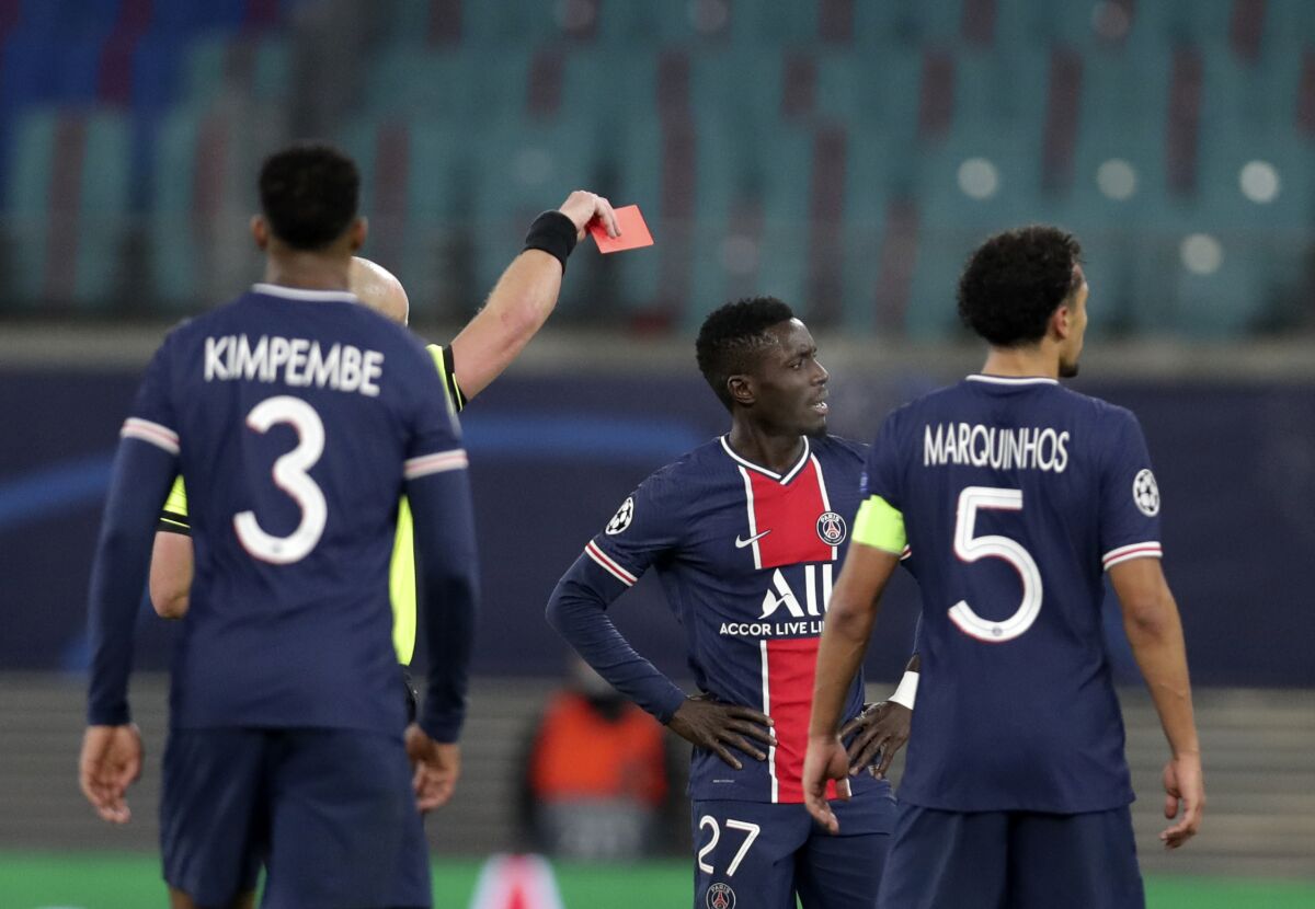 Referee Szymon Marciniak shows a red card to PSG's Idrissa Gueye, second right, during the Champions League group H soccer match between RB Leipzig and Paris Saint Germain at the RB Arena in Leipzig, Germany, Wednesday, Nov. 4, 2020. (AP Photo/Michael Sohn)