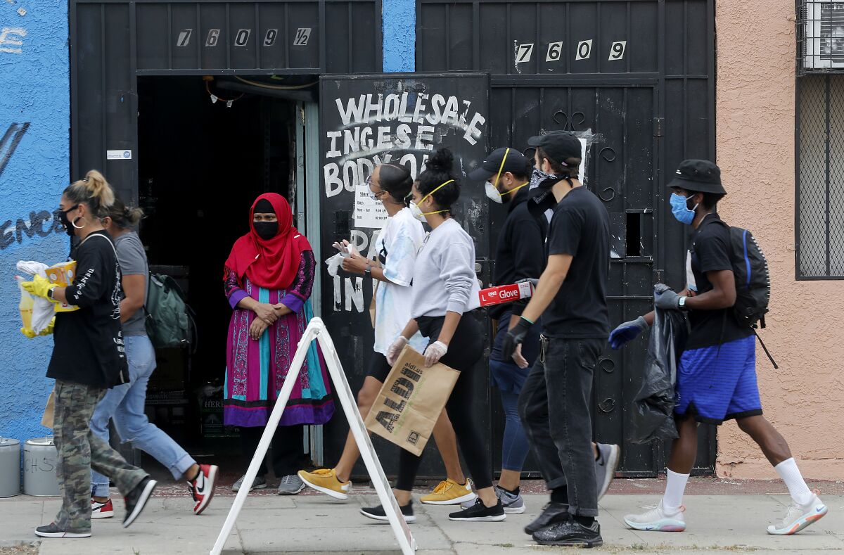 A woman looks on as volunteers clean a stretch of Western Avenue in South L.A.
