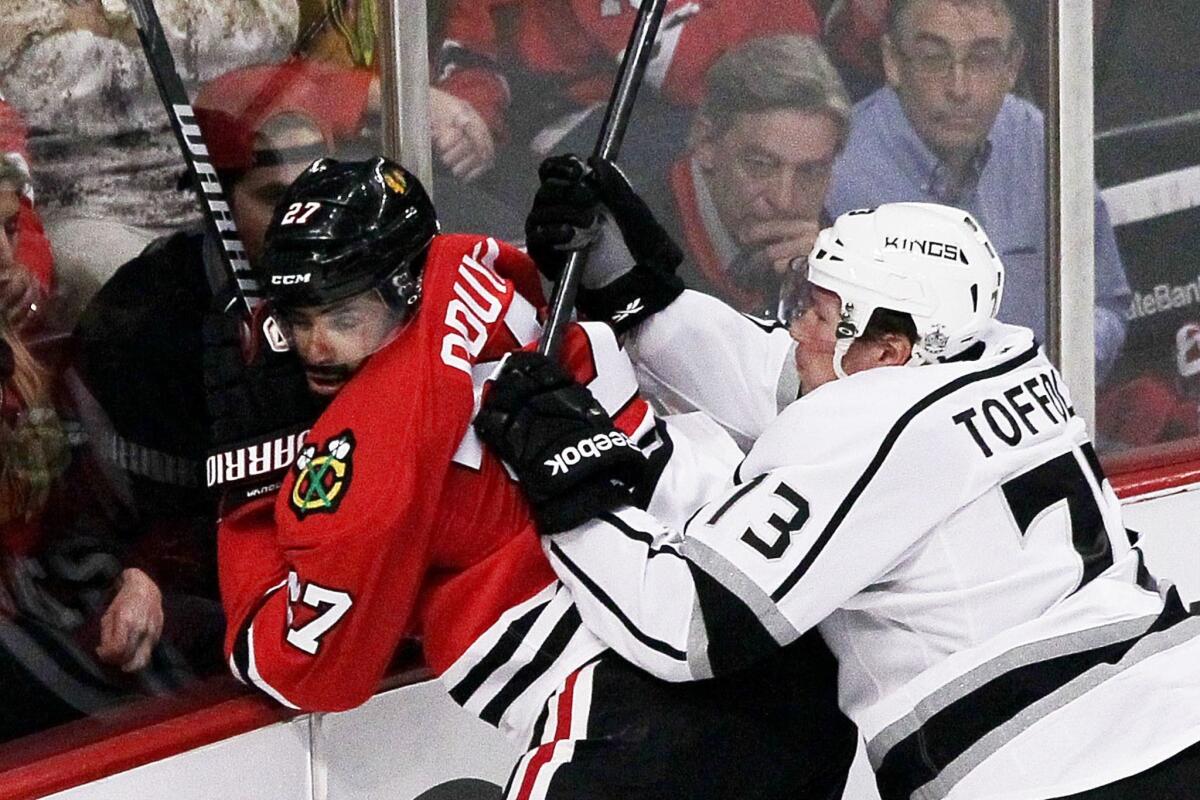 Kings left wing Kyle Clifford checks Blackhawks defenseman Johnny Oduya into the boards in the second period.