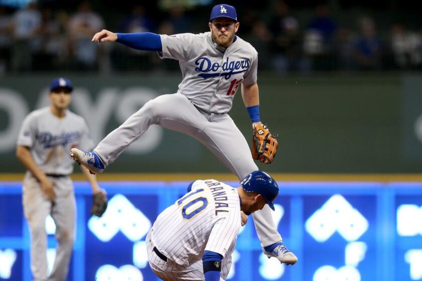 MILWAUKEE, WISCONSIN - APRIL 19: Max Muncy #13 of the Los Angeles Dodgers turns a double play past Yasmani Grandal #10 of the Milwaukee Brewers in the sixth inning at Miller Park on April 19, 2019 in Milwaukee, Wisconsin. (Photo by Dylan Buell/Getty Images) ** OUTS - ELSENT, FPG, CM - OUTS * NM, PH, VA if sourced by CT, LA or MoD **