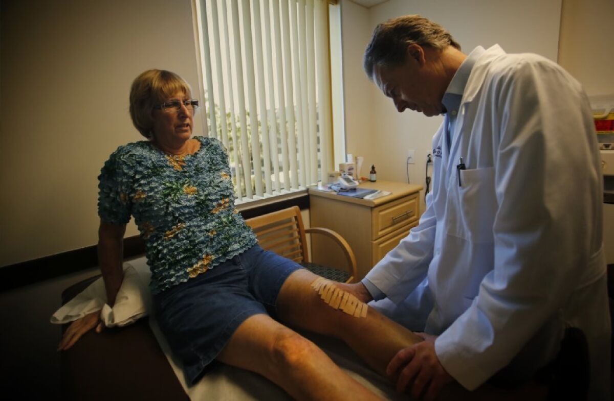 Orthopedic surgeon James Caillouette, right, examines Carolyn Rondou after her knee replacement surgery at Hoag Orthopedic Institute in Irvine in 2014.