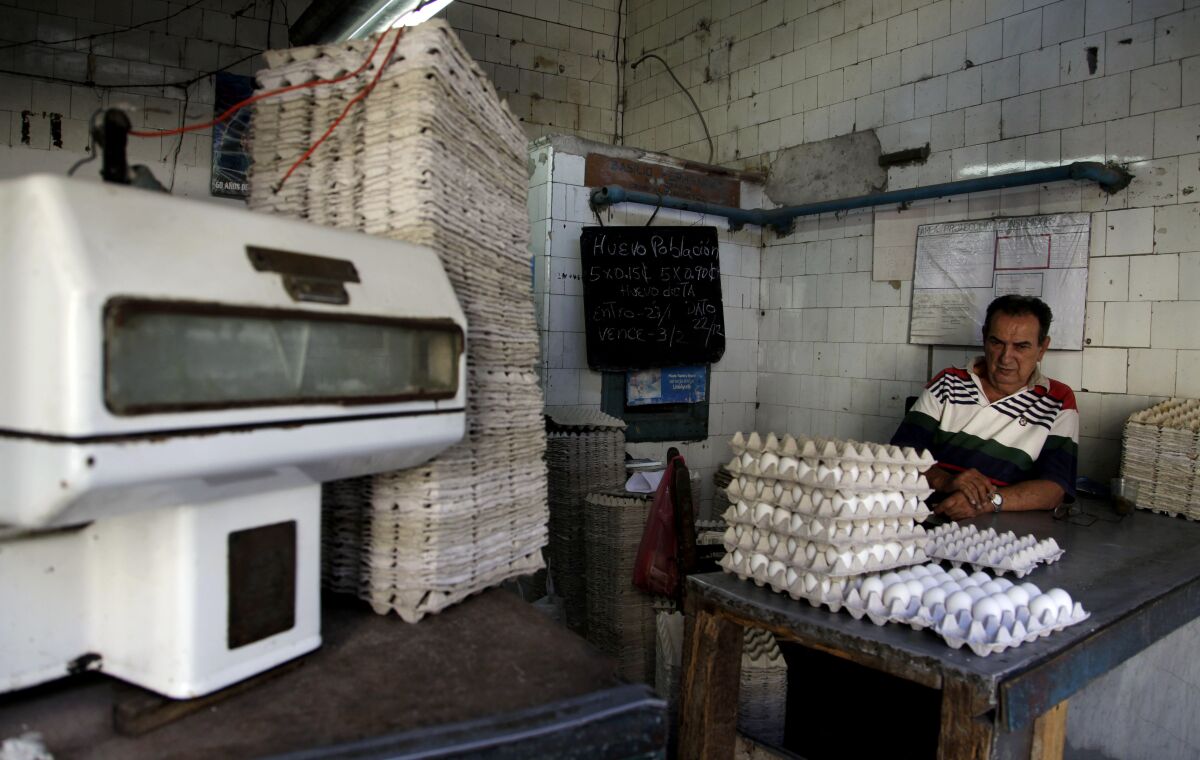 A man sits against a wall looking at stacked crates of eggs
