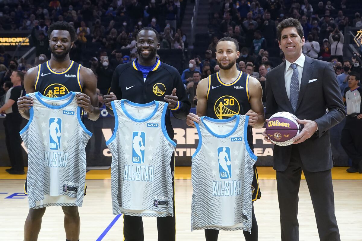 Golden State Warriors' Andrew Wiggins, Draymond Green, Stephen Curry and general manager Bob Myers, from left, pose while the players were presented All-Star Game jerseys, before the team's NBA basketball game against the Denver Nuggets in San Francisco, Wednesday, Feb. 16, 2022. (AP Photo/Jeff Chiu)