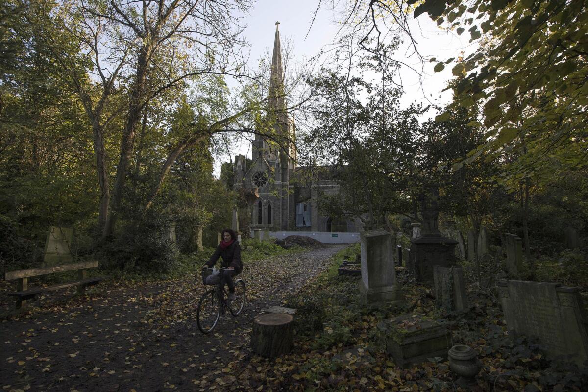 A cyclist rides through Abney Park Cemetery in London.