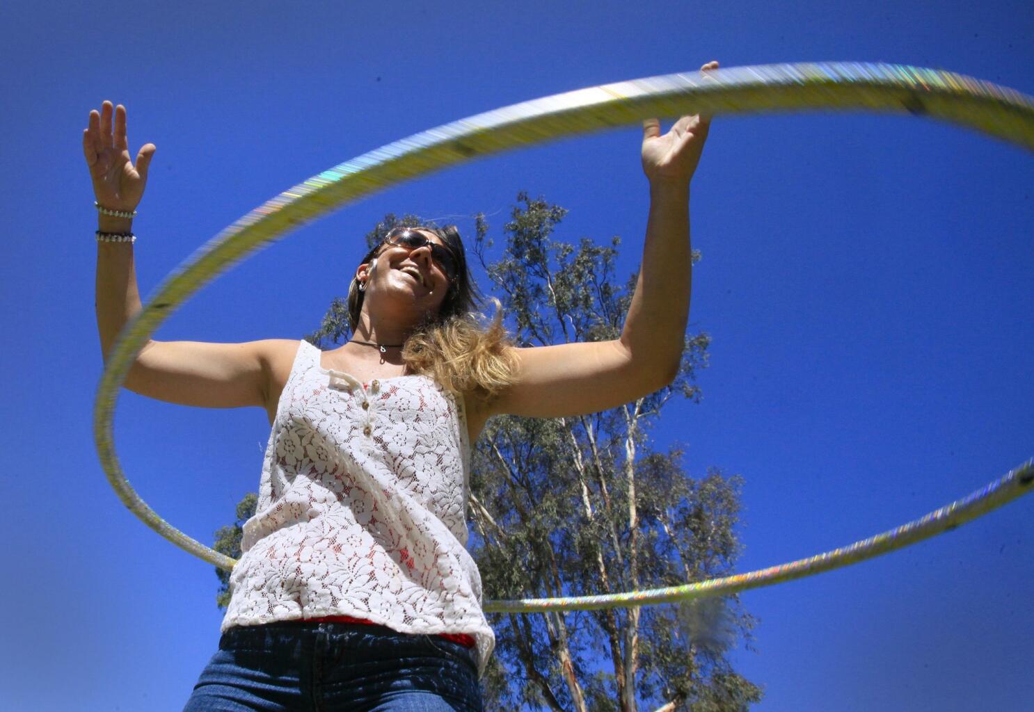 Niña deportiva haciendo ejercicio con hula hoop sobre fondo de parque