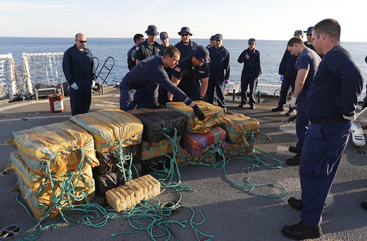 U.S. Coast Guard members gather around seized bales of cocaine.