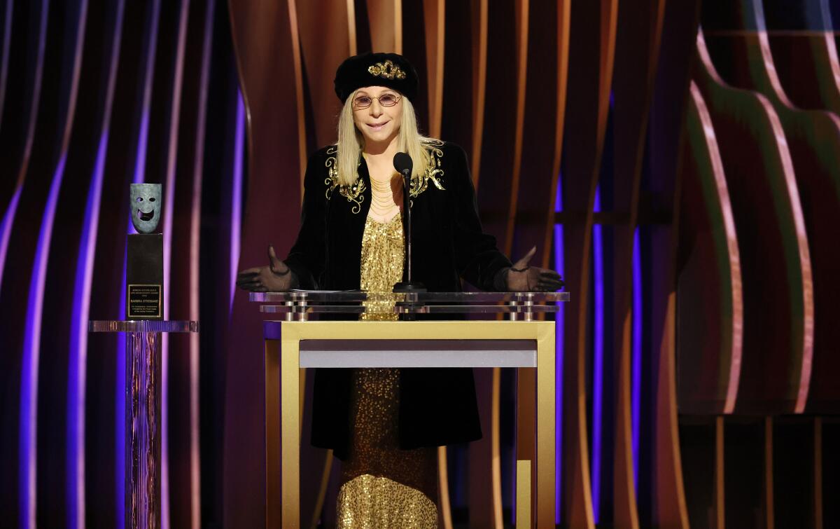 A woman in a black hat stands at a podium.