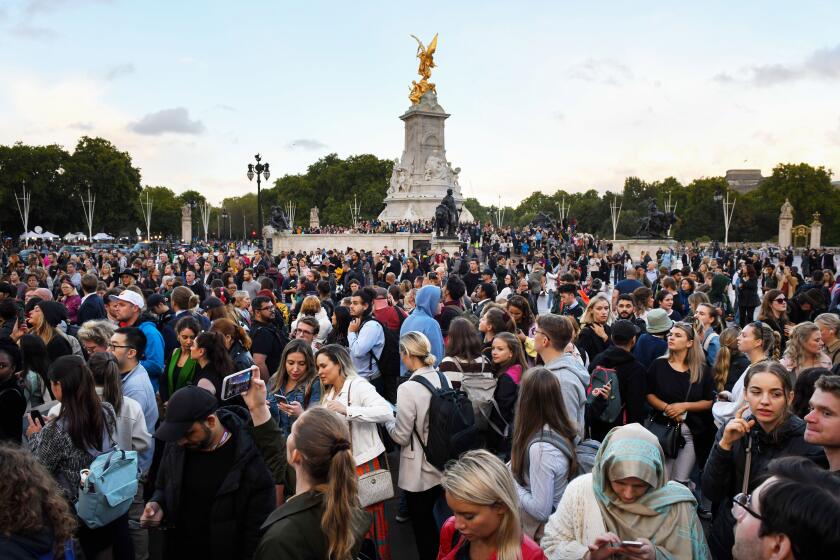 Tourists and well wishers gather near the Queen Victoria Memorial outside Buckingham Palace following the announcement of the death of Queen Elizabeth II in London, UK, on Thursday, Sept. 8, 2022. Queen Elizabeth II, whose reign took Britain from the age of steam to the era of the smartphone, and who oversaw the largely peaceful breakup of an empire that once spanned the globe, has died. Photographer: Chris J. Ratcliffe/Bloomberg via Getty Images