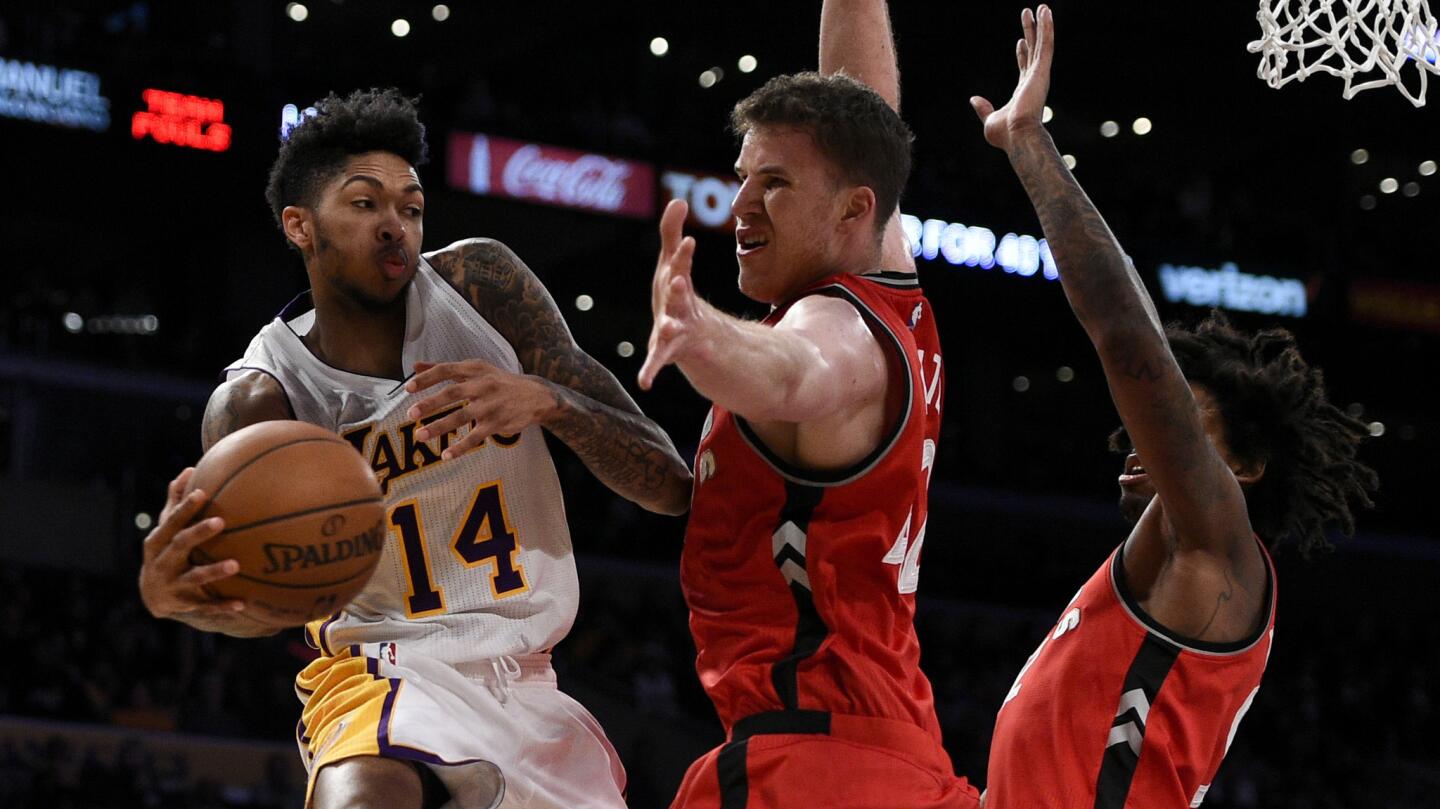 Lakers forward Brandon Ingram, left, passes the ball after driving the baseline against Raptors center Jakob Poeltl during the second half.