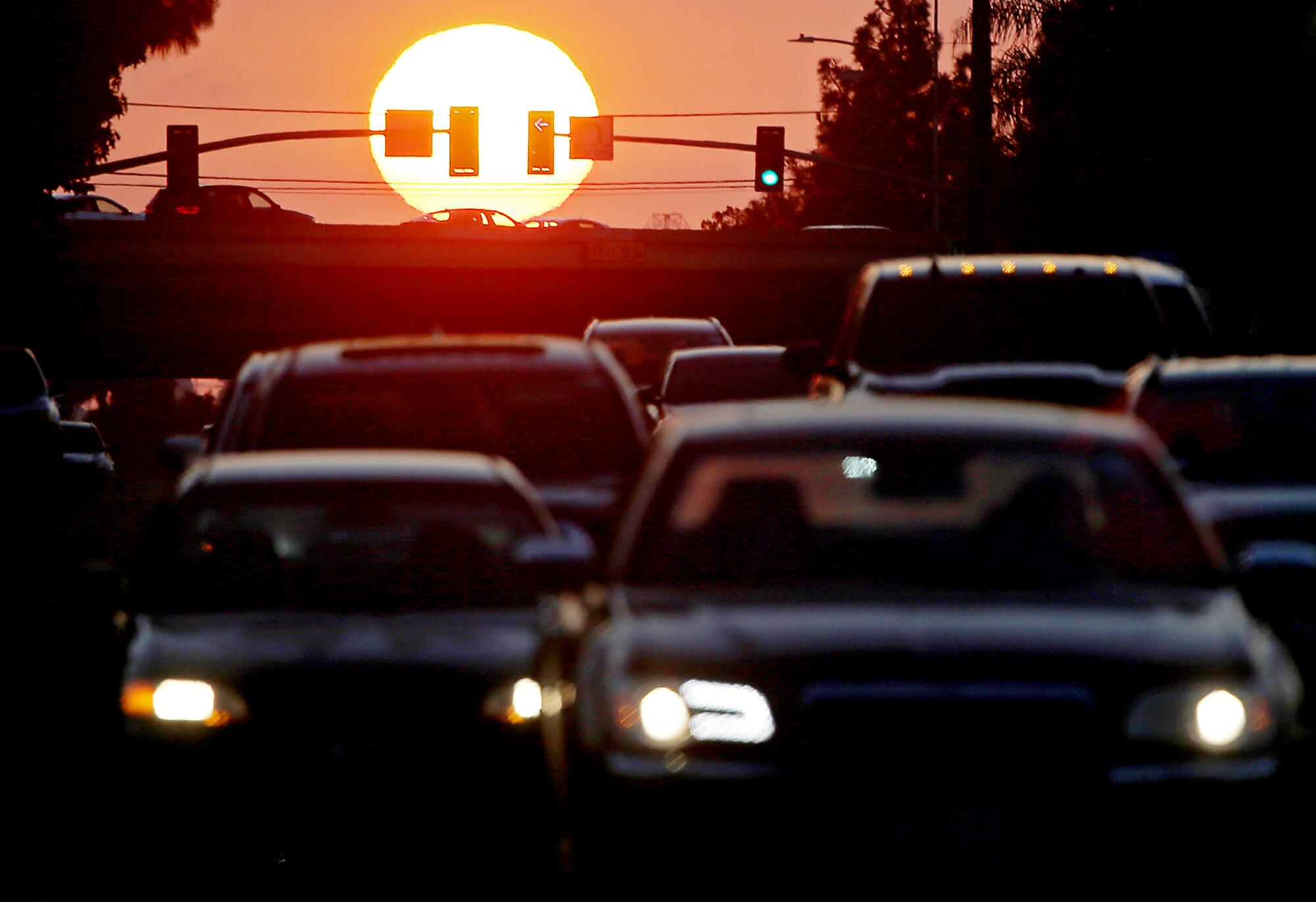 Traffic stacks up in Long Beach as a glowing-orange sun sets. 