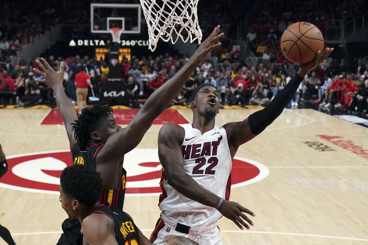 Miami Heat forward Jimmy Butler (22) shoots as Atlanta Hawks center Clint Capela (15) defends in the first half of an NBA playoff basketball game Sunday, April 24, 2022, in Atlanta. (AP Photo/John Bazemore)