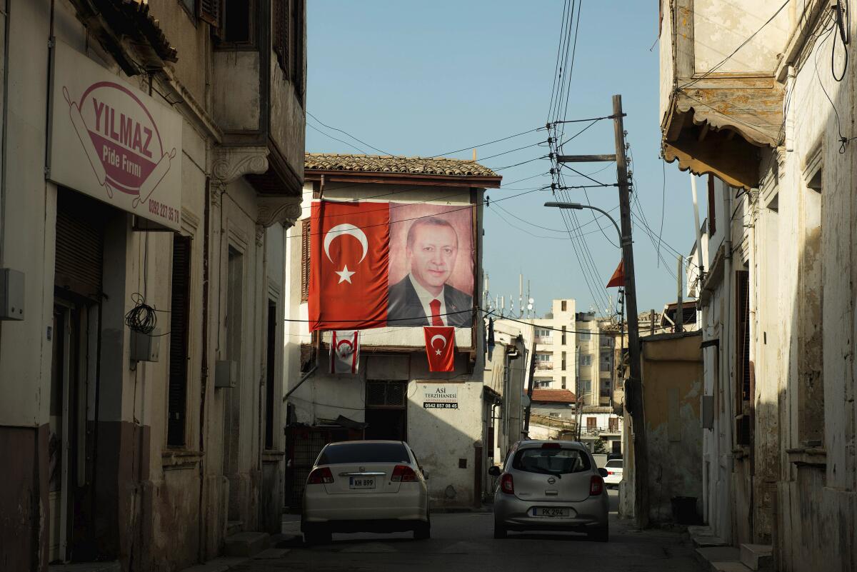 FILE - A portrait of Turkish President Recep Tayip Erdogan and Turkish flags are seen on a building in the Turkish occupied area at the Turkish Cypriot breakaway north part of divided capital Nicosia, Cyprus, Wednesday, March 10, 2021. The president of ethnically divided Cyprus says he will lodge a complaint with the United Nations over Turkey’s new financial assistance deal with breakaway Turkish Cypriots. (AP Photo/Nedim Enginsoy, File)