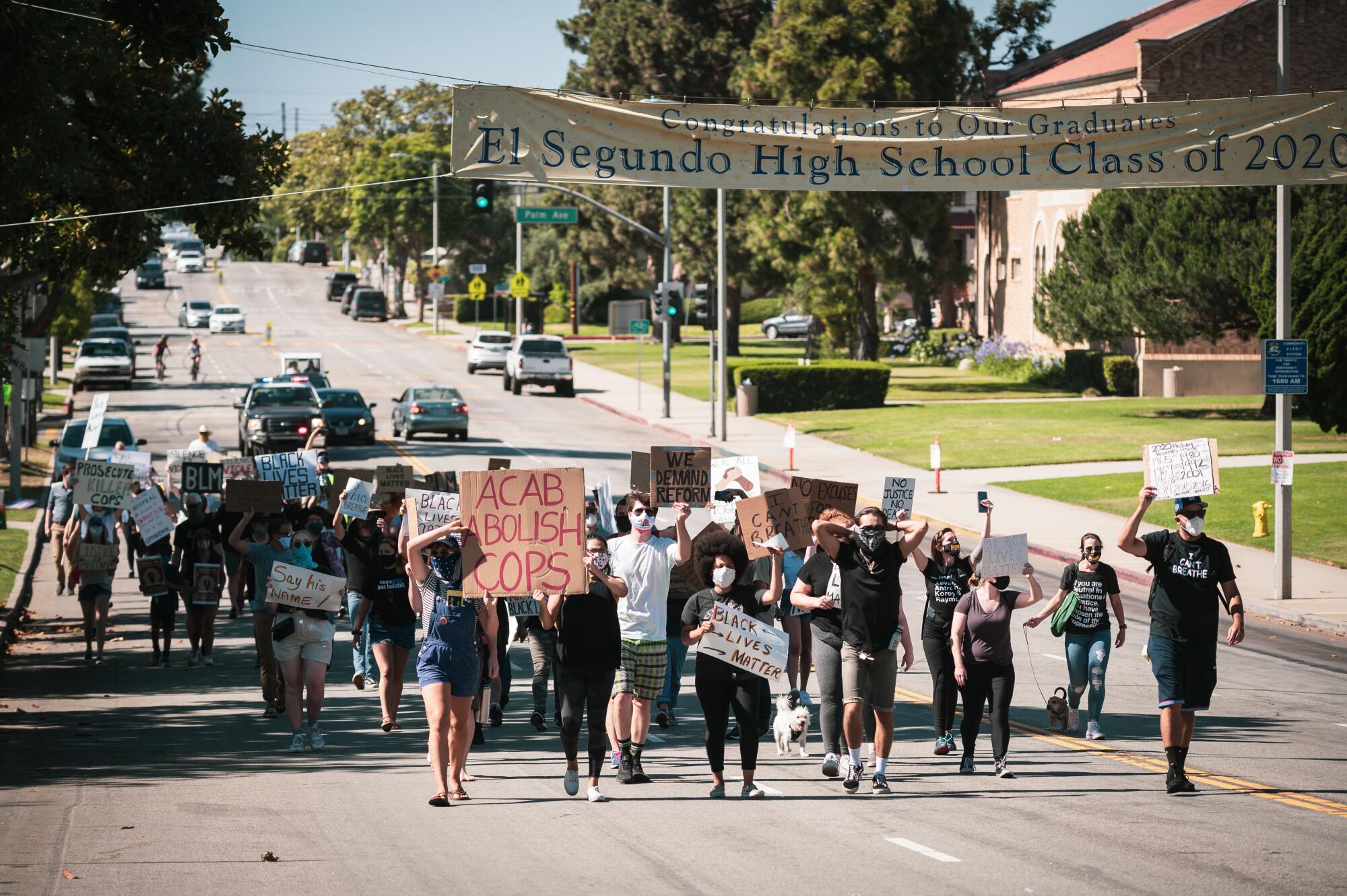 A group of people holding signs walk down a street