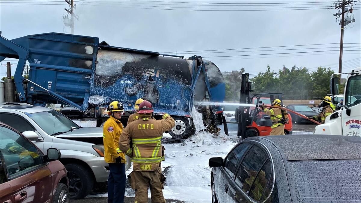 Crews work at a Costa Mesa tow yard Monday to completely douse flames inside a commercial trash truck, officials reported.