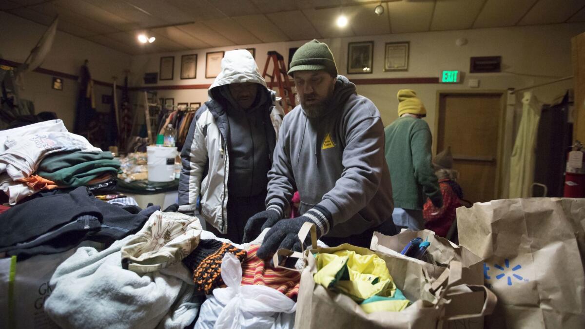 Sean Davis, right, helps a man find a hat in piles of donated clothes at American Legion Post 134 in Portland.