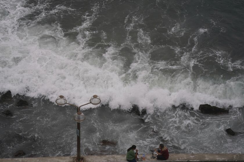 People relax at the beach front in Mazatlan, Mexico, Sunday, Oct. 2, 2022. Hurricane Orlene, at Category 3 strength, is heading for a collision with Mexico's northwest Pacific coast between the tourist towns of Mazatlan and San Blas. (AP Photo/Fernando Llano)