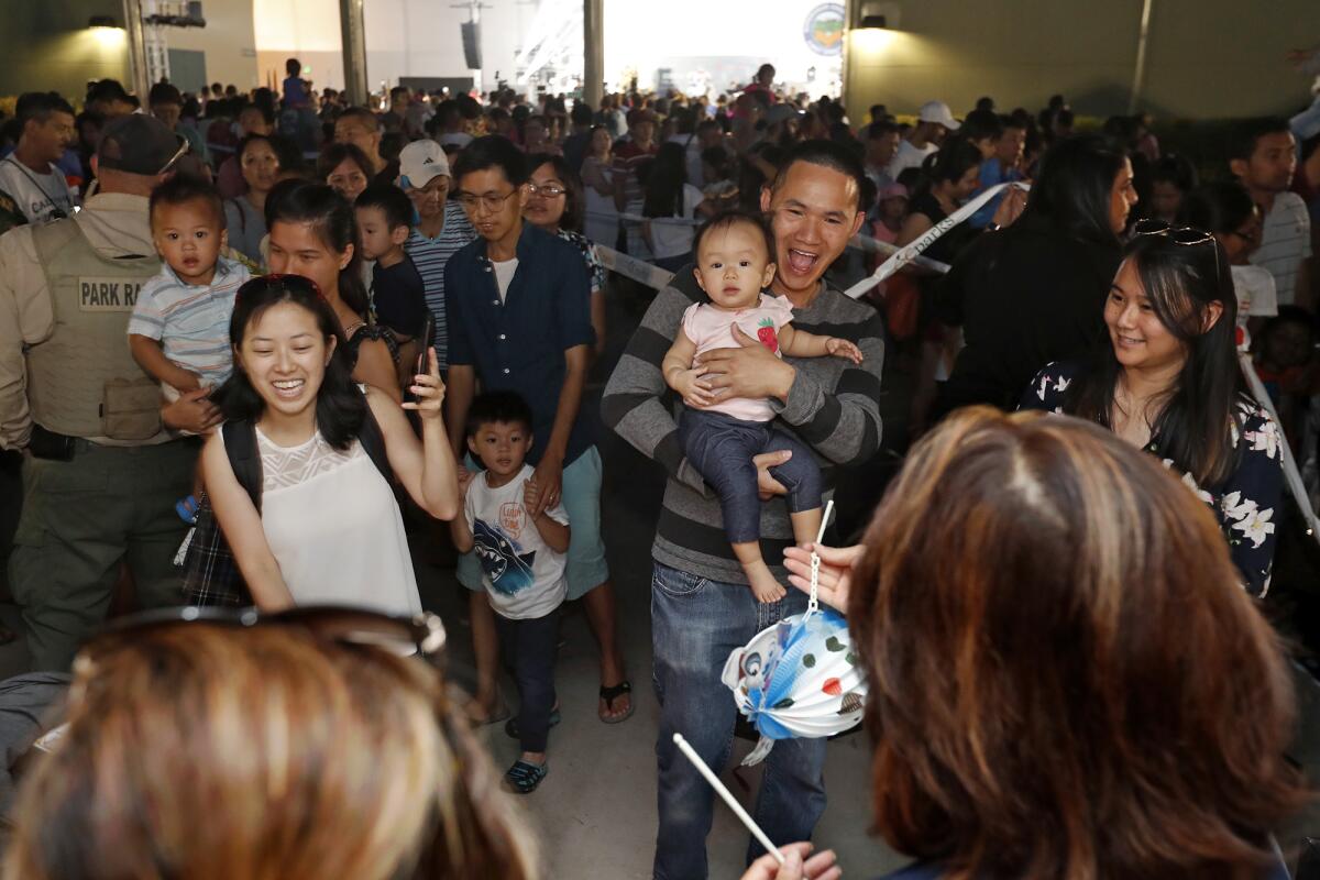 Children receive a free paper lantern and mooncake as part of the Moon Festival celebration.