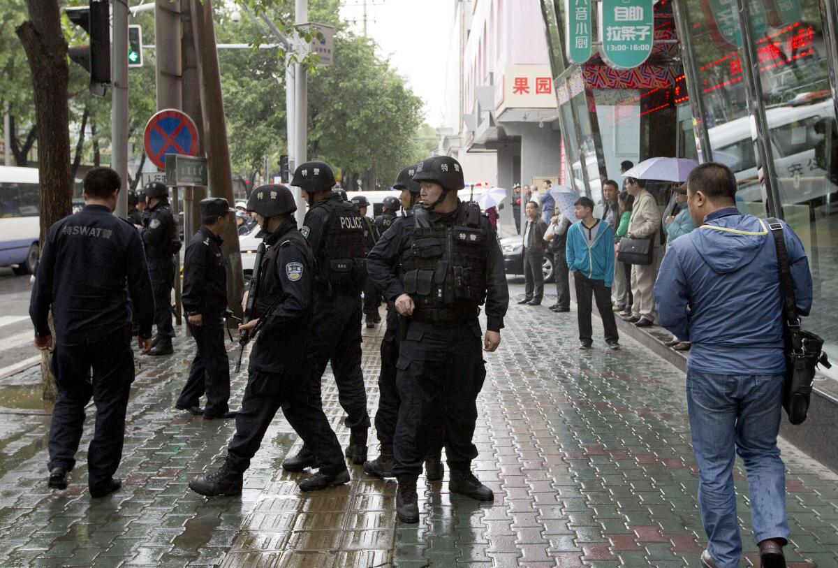 Armed policemen stand guard near the site of an explosion Thursday in Urumqi, China.