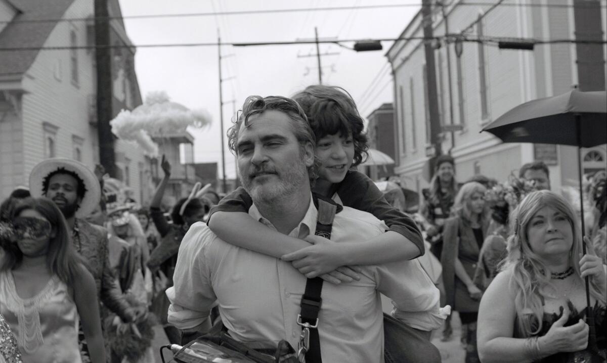 A man in a crowd gives a young boy a piggyback ride 