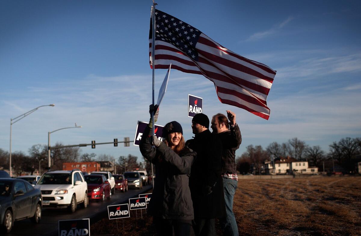 Supporters of Republican presidential candidate Rand Paul campaign on a street corner during the morning rush hour in Des Moines on Feb. 1.