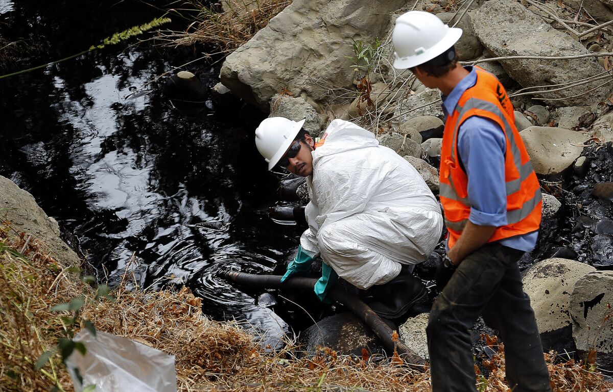 A contractor guides a hose into Prince Barranca gorge in Ventura to pump out oil that spilled
