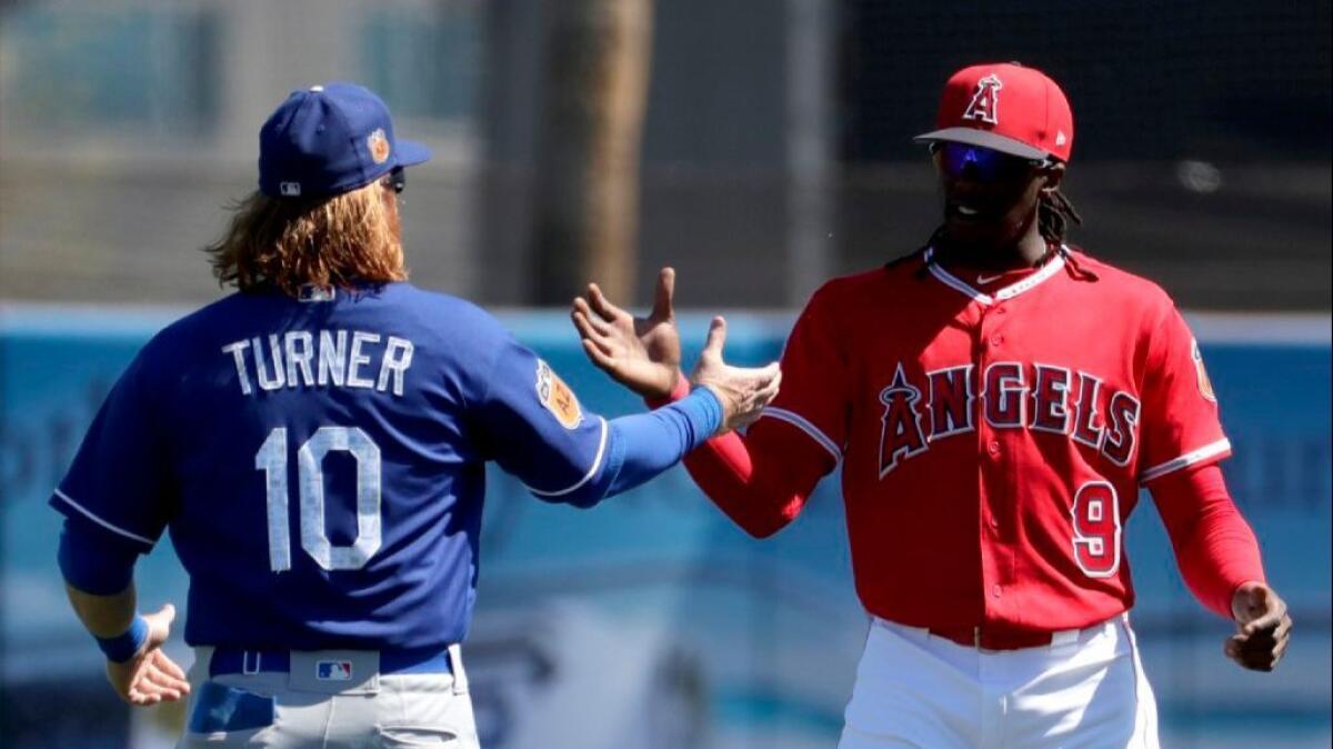 Dodgers third baseman Justin Turner and Angels outfielder Cameron Maybin greet each other during a spring-training game.